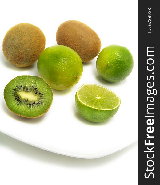 A group of fresh kiwis and limes on a white plate and isolated on white background. A group of fresh kiwis and limes on a white plate and isolated on white background