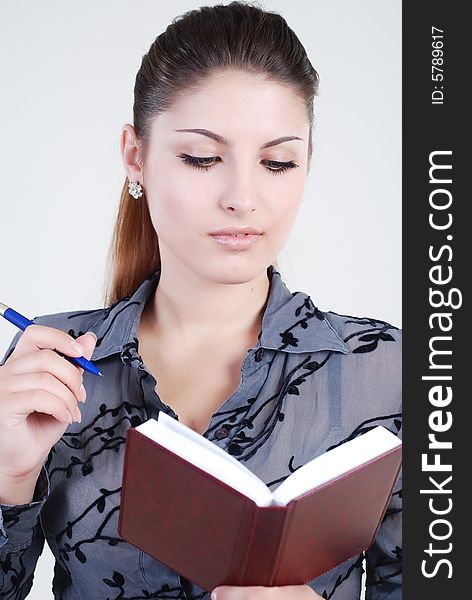 Beautiful young girl in a grey business suit with a diary and writing pen in hands. Beautiful young girl in a grey business suit with a diary and writing pen in hands