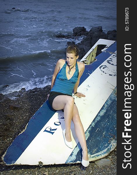Model sitting on an old rusty boat by the water. Model sitting on an old rusty boat by the water