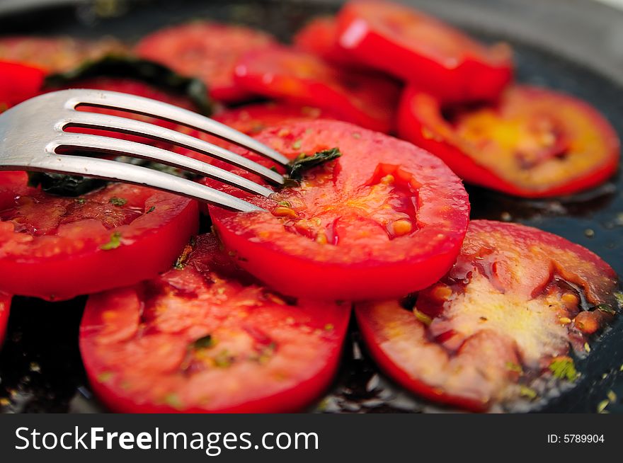 Tomato slices salad with basil and some other spices, all with a fork. Tomato slices salad with basil and some other spices, all with a fork.