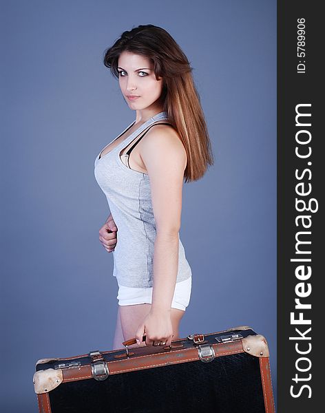 A girl in a grey shirt with beautiful hair holds a suitcase in a hand and looks a sure look. A girl in a grey shirt with beautiful hair holds a suitcase in a hand and looks a sure look