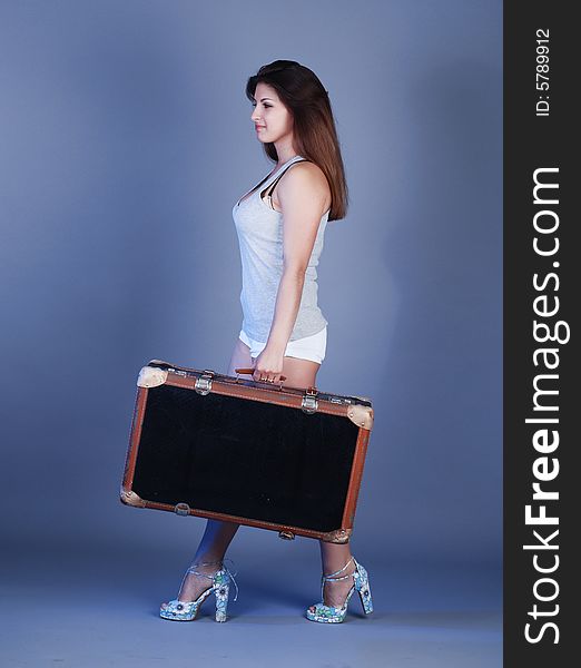 A girl in a grey shirt with beautiful hair holds a suitcase in a hand. A girl in a grey shirt with beautiful hair holds a suitcase in a hand