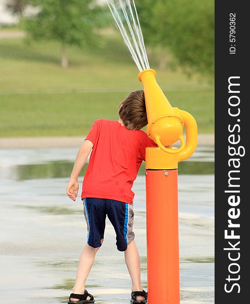Portrait of a young boy playing with a water canon at an outdoor Spray Park