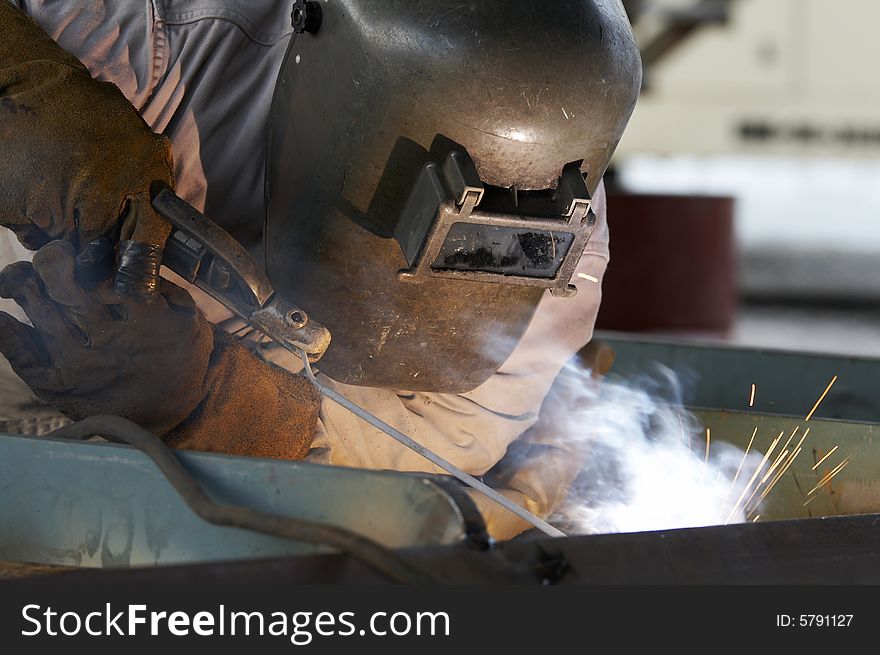 A welder working at shipyard during day shift. A welder working at shipyard during day shift