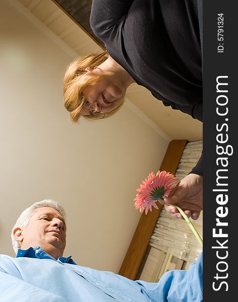 A man, gives a woman a pink flower, the camera is below them, looking up. - vertically framed. A man, gives a woman a pink flower, the camera is below them, looking up. - vertically framed