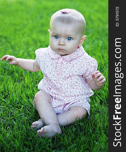 A young baby, crosses her legs while sitting, and has a confused look on her face. Vertically framed shot. A young baby, crosses her legs while sitting, and has a confused look on her face. Vertically framed shot.