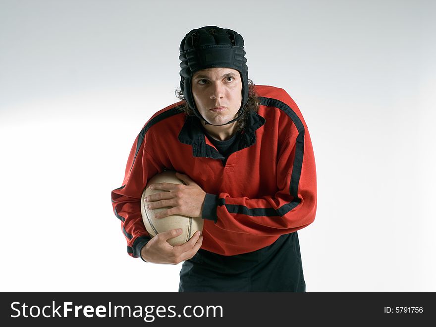 A man, wearing a full rugby uniform, holds the ball tightly, while having a serious look on his face. Horizontally framed shot. A man, wearing a full rugby uniform, holds the ball tightly, while having a serious look on his face. Horizontally framed shot.