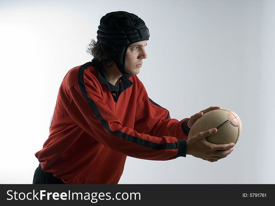 A young man, dressed in a rugby outfit, prepares to kick the ball, looking serious. Horizontally framed shot. A young man, dressed in a rugby outfit, prepares to kick the ball, looking serious. Horizontally framed shot.