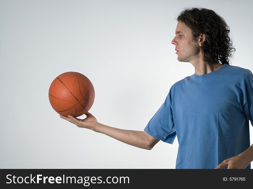 A man, looking intently at the basketball, holds the basketball out away from him. Horizontally framed shot. A man, looking intently at the basketball, holds the basketball out away from him. Horizontally framed shot.