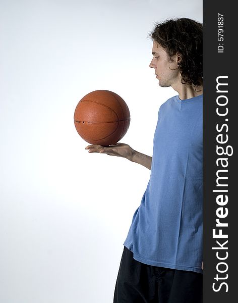 Man holding a basketball and balancing it as he stares at it. Vertically framed photograph. Man holding a basketball and balancing it as he stares at it. Vertically framed photograph