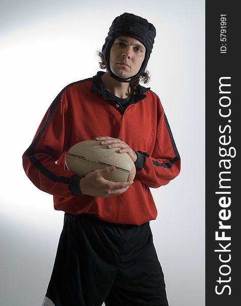 A man, wearing a full rugby outfit, looks serious as he holds the rugby ball. Vertically framed shot. A man, wearing a full rugby outfit, looks serious as he holds the rugby ball. Vertically framed shot.