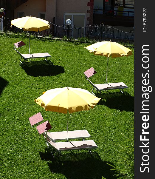 A relaxing shot of some beach umbrellas and camp beds in a lawn. A relaxing shot of some beach umbrellas and camp beds in a lawn