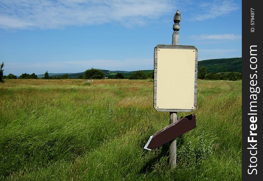 Wooden sign with arrow on green field. Wooden sign with arrow on green field