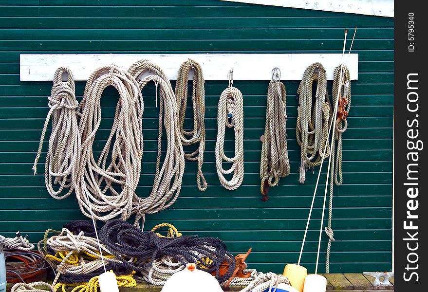 View of various ropes hanging and others on the ground in a fishing harbor.