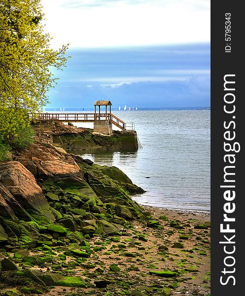 Seascape of rocky shore with distant sail boats. Seascape of rocky shore with distant sail boats.