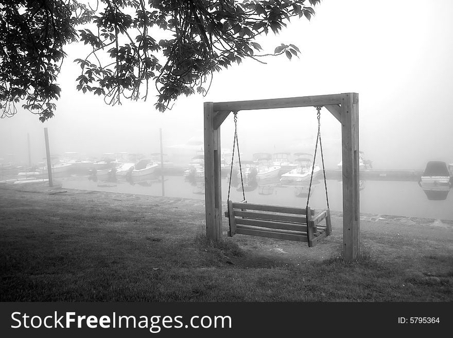 View of foggy marina and empty wooden swing. View of foggy marina and empty wooden swing
