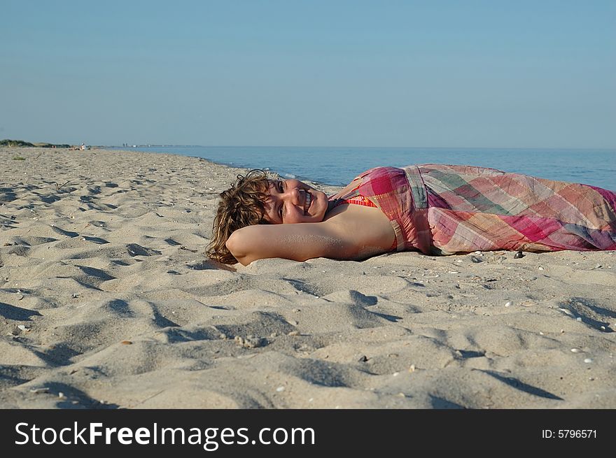 Smiling,laughing girl lying on the beach during sunset. Smiling,laughing girl lying on the beach during sunset