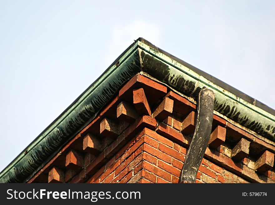 Corner of building showing brick work and oxidized copper flashing and drain. Corner of building showing brick work and oxidized copper flashing and drain