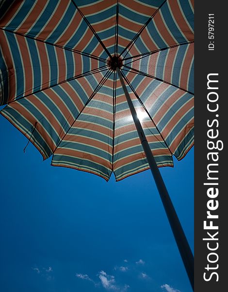 Beach umbrella is displayed against a background of blue Sky. Beach umbrella is displayed against a background of blue Sky