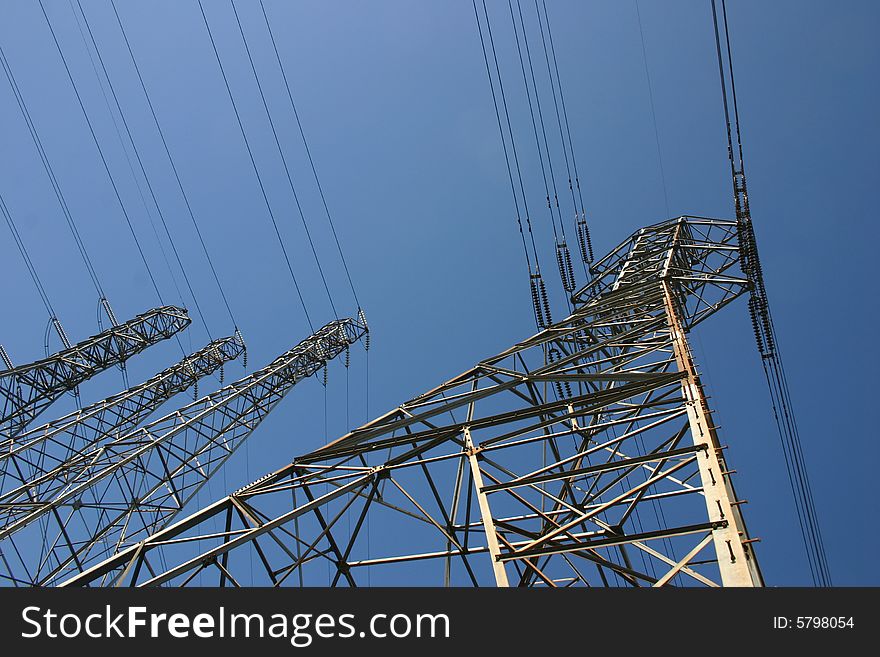 Towers and high tension lines against a blue sky. Towers and high tension lines against a blue sky