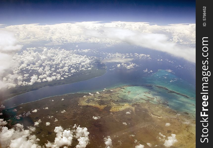Tropical Land and Ocean through the clouds from above. Tropical Land and Ocean through the clouds from above