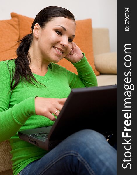 Attractive brunette woman on sofa with laptop. Attractive brunette woman on sofa with laptop