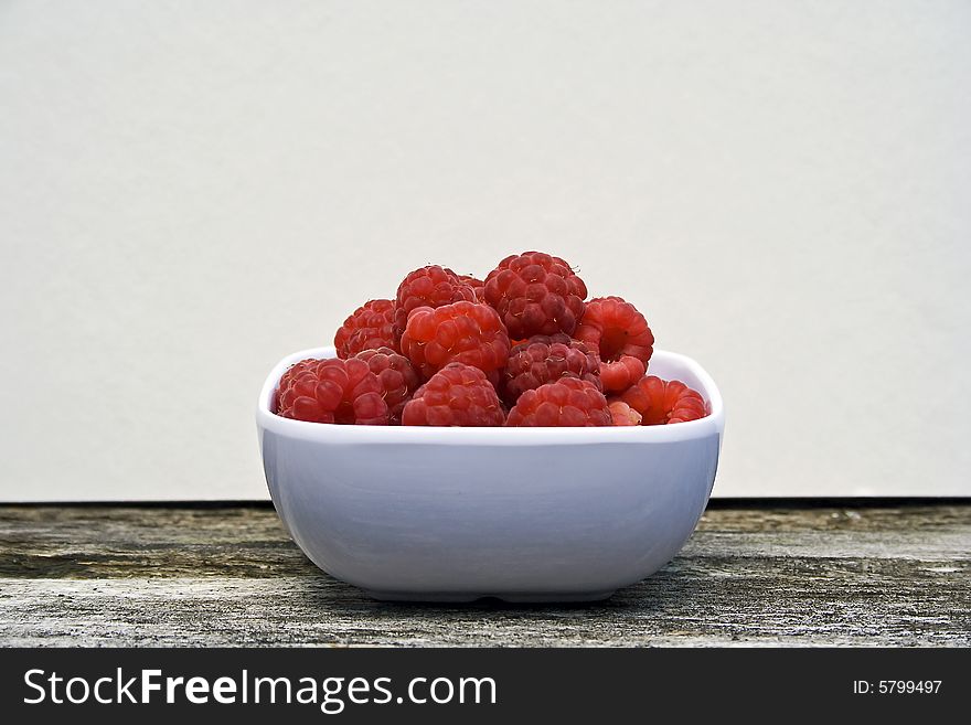 White bowl with red raspberries