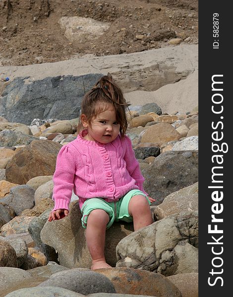 Child sitting on a rocky beach. Child sitting on a rocky beach