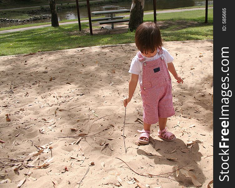 Toddler drawing in the sand with a stick