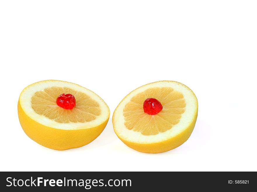Two grapefruit halves with a red cherry on top of each, against a white background. Two grapefruit halves with a red cherry on top of each, against a white background.