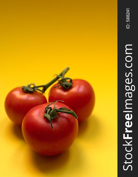 Three fresh and ripe tomatoes against yellow background, Great for advertisement!. Three fresh and ripe tomatoes against yellow background, Great for advertisement!