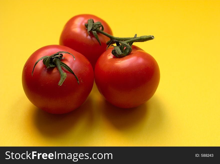 Three fresh and ripe tomatoes against yellow background, Great for advertisement!. Three fresh and ripe tomatoes against yellow background, Great for advertisement!