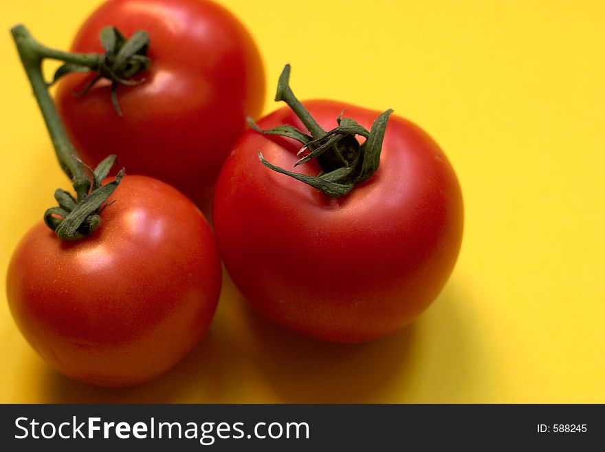 Three fresh and ripe tomatoes against yellow background, Great for advertisement!. Three fresh and ripe tomatoes against yellow background, Great for advertisement!