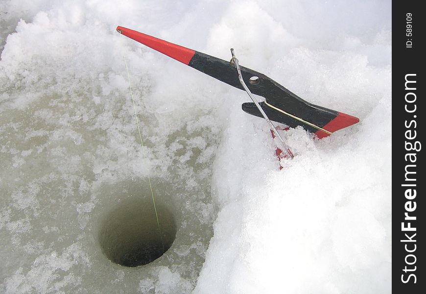 Home made ice fishing equipment and a fishing hole on a frozen lake