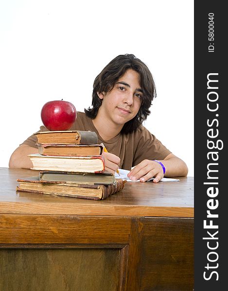 Teenager boy sitting by his desk with a red apple on pile of books. Teenager boy sitting by his desk with a red apple on pile of books