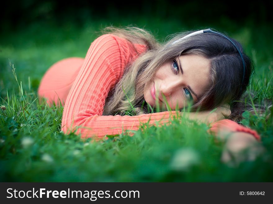 Relaxed young woman listening music cat clover meadow