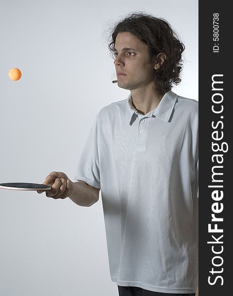 Man bounces a ping pong ball on a paddle. He wears a look of concentration. Vertically framed photograph. Man bounces a ping pong ball on a paddle. He wears a look of concentration. Vertically framed photograph