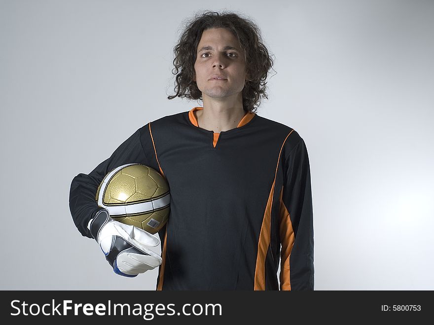 Soccer player in a soccer uniform holds a soccer ball and has a serious expression on his face. Horizontally framed photograph. Soccer player in a soccer uniform holds a soccer ball and has a serious expression on his face. Horizontally framed photograph.