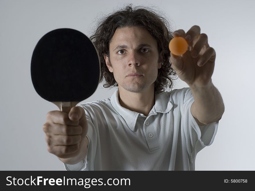 Man holding a table tennis ball and paddle out in front of him with a serious look on his face. Horizontally framed photograph. Man holding a table tennis ball and paddle out in front of him with a serious look on his face. Horizontally framed photograph