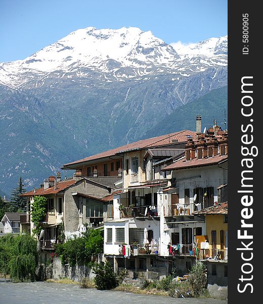 A small village alongside a river with the Italian Alps in the background. A small village alongside a river with the Italian Alps in the background