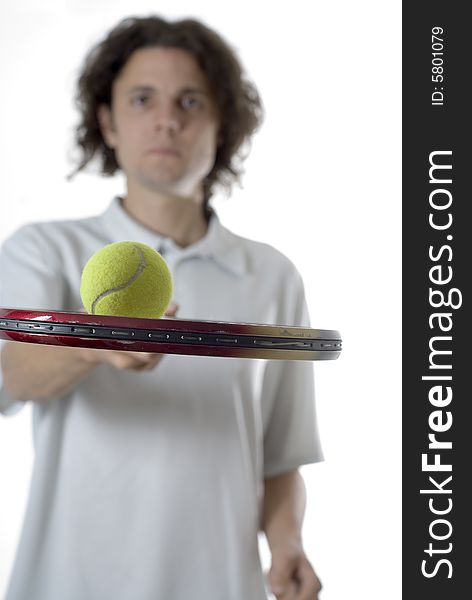 Man balancing a tennis ball on a tennis racket with a serious look on his face. Vertically framed photograph. Man balancing a tennis ball on a tennis racket with a serious look on his face. Vertically framed photograph
