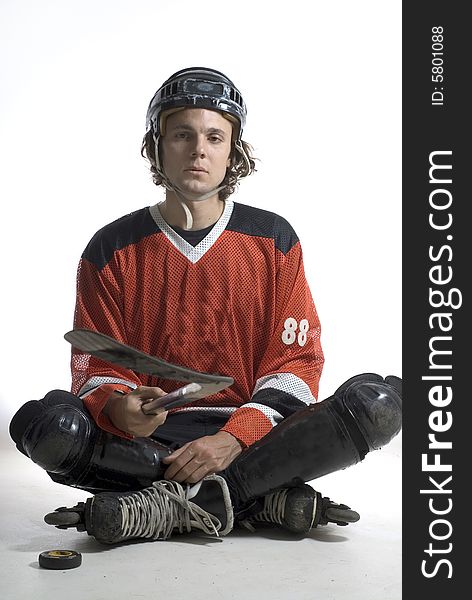 Man appears sad as he sits on the floor holding a hockey stick. Vertically framed photograph. Man appears sad as he sits on the floor holding a hockey stick. Vertically framed photograph