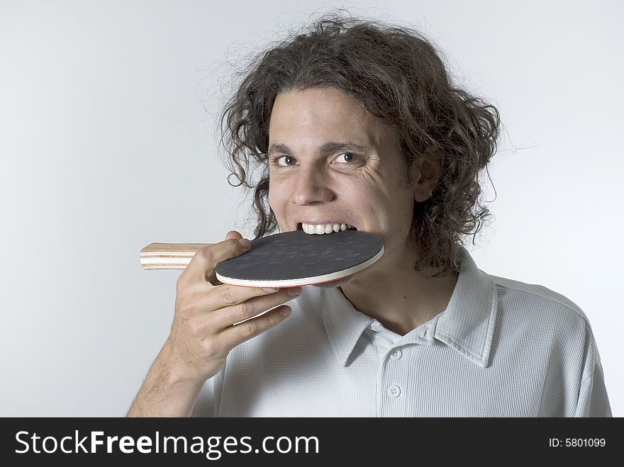 Man puts a table tennis paddle in his mouth. Horizontally framed photograph. Man puts a table tennis paddle in his mouth. Horizontally framed photograph