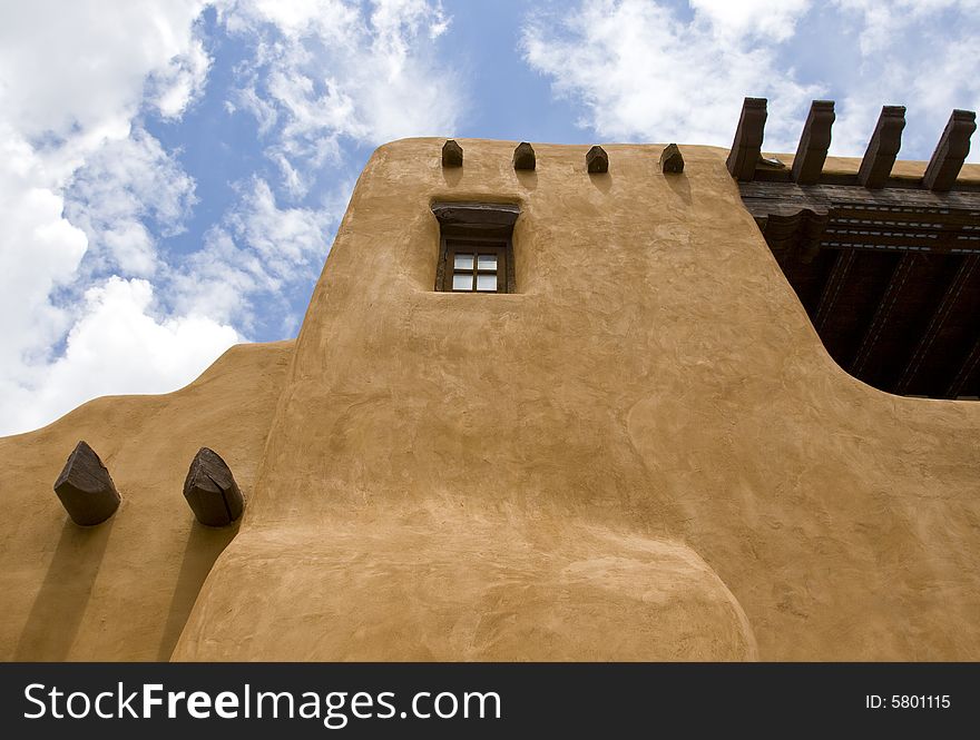 Adobe building with exposed wood beams under a blue sky