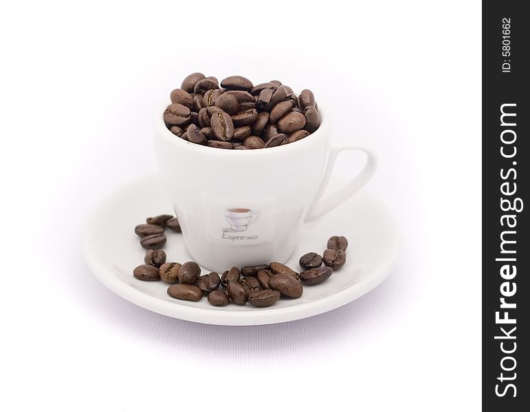 An espresso cup over flowing with beans. An espresso cup over flowing with beans