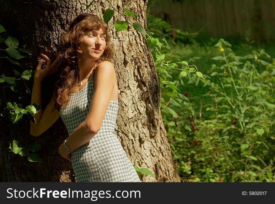 Sexy girl against tree trunk in woods.