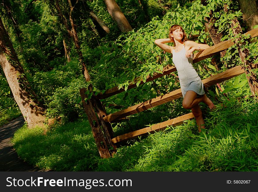 Pretty girl leaning against fence in woods. Pretty girl leaning against fence in woods.