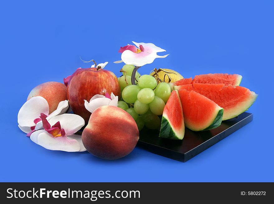 Composition from fruit, baccas of a lemon and an orchid on a black support. Composition from fruit, baccas of a lemon and an orchid on a black support