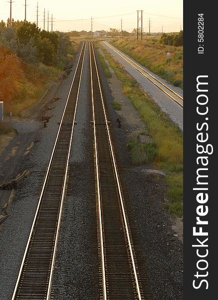 Three train tracks stretch into the distance at sunset.