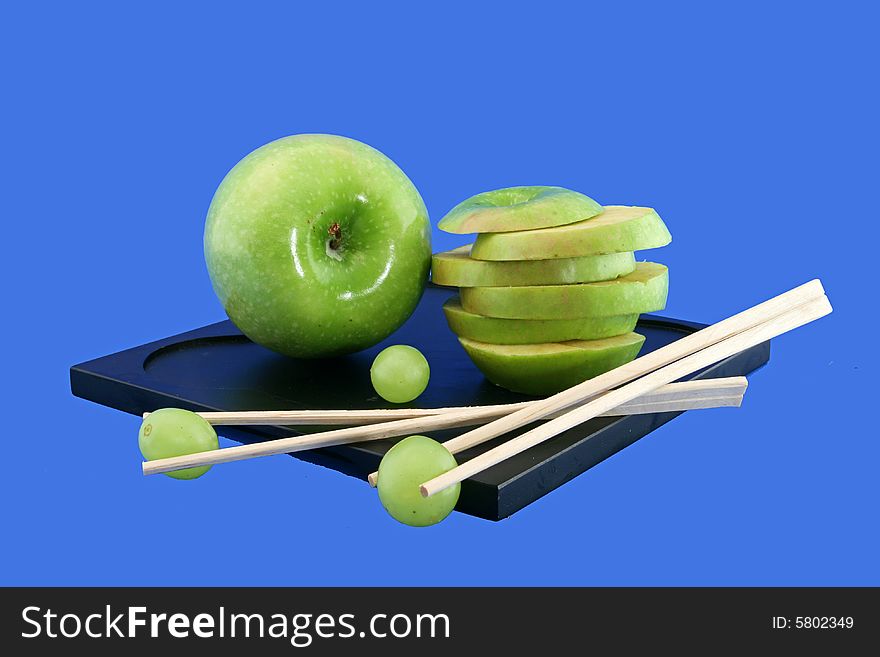 Composition on a black support from segments of a green pome and the Chinese rods with grapes. Composition on a black support from segments of a green pome and the Chinese rods with grapes